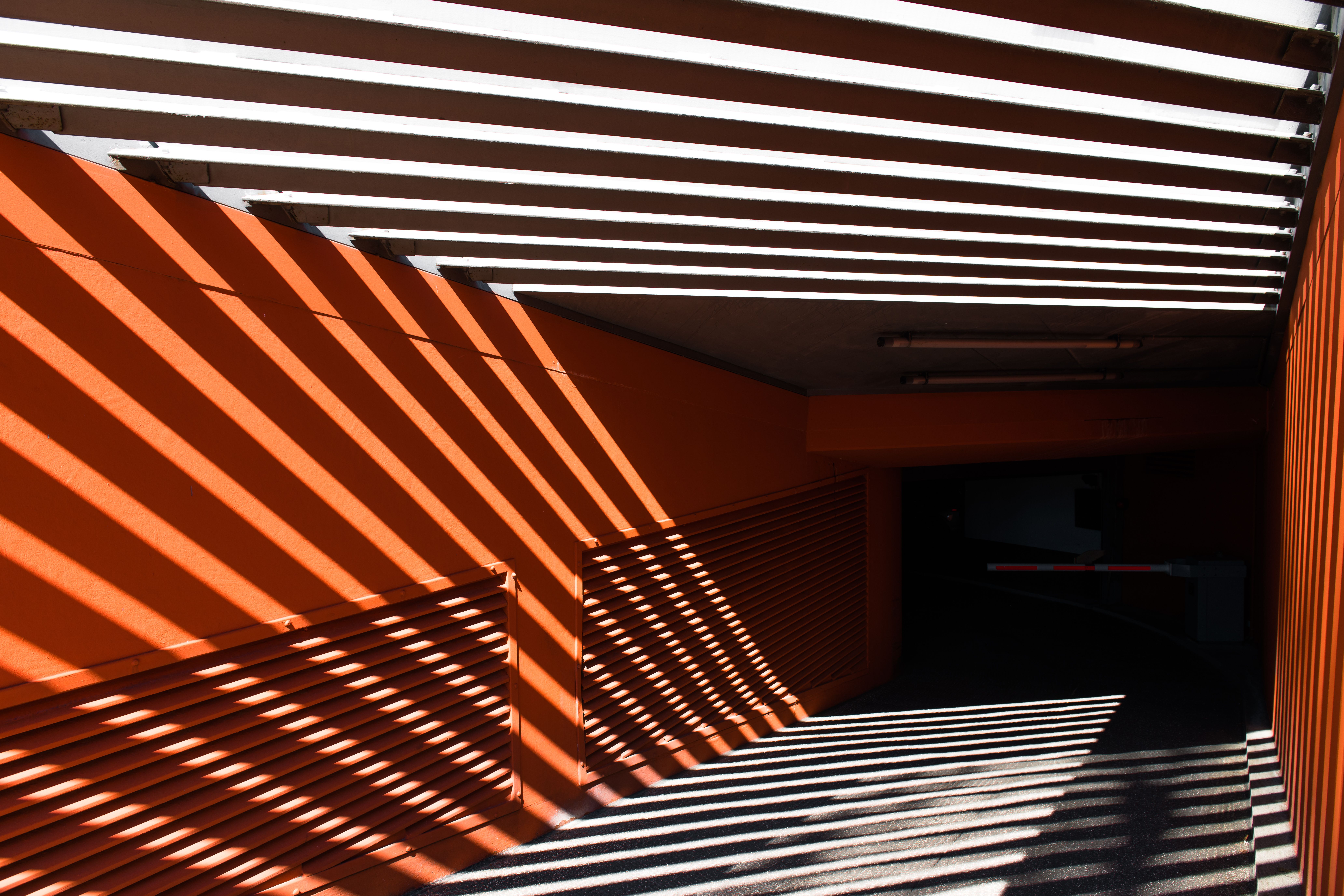 Bands of sunlight and shadow across an orange concrete wall